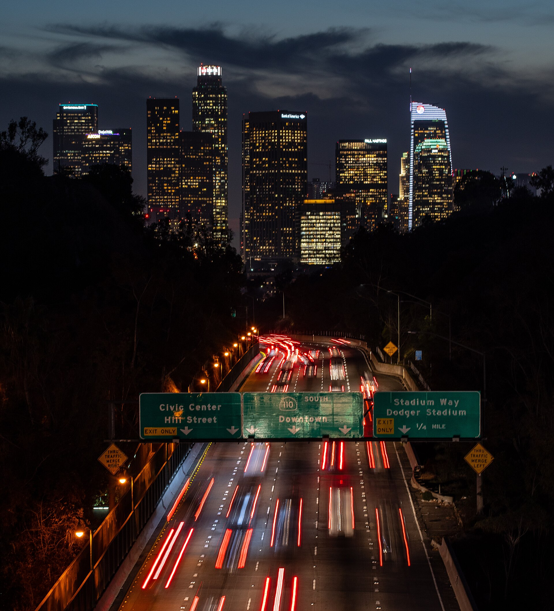 Downtown Los Angeles skyline at night as seen from Park Row Bridge in Elysian Park neighborhood, with the 110 Freeway South in view.